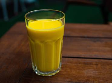 a tall glass of a creamy mango smoothie