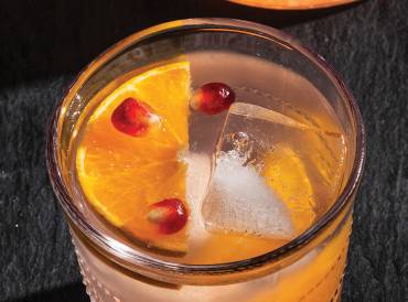 a glass of citrus and pomegranate mocktail