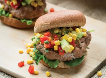 turkey burgers stacked tall with avocado, corn, and peppers