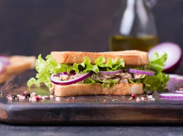 a tuna salad sandwich with red onion and lettuce