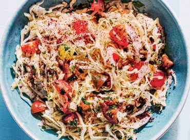 a bowl of cabbage, cherry tomatoes, parsley, and spices