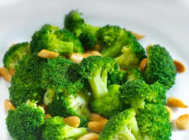 a bowl of broccoli and chopped nuts