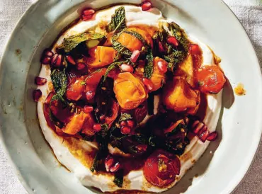 a plate of grilled tomatoes on a bed of yogurt