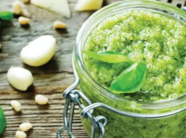 A canning jar of fresh basil pesto with garlic and cheese