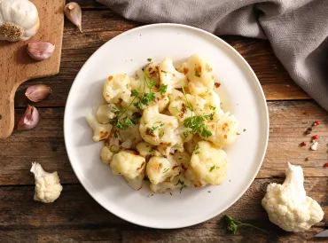 grilled cauliflower plated with a garnish