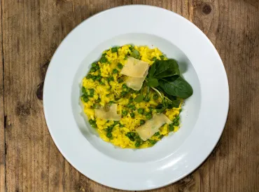 a bowl of risotto with leeks, peas, garnish, and cheese