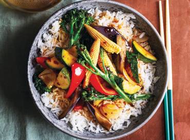 a bowl of stir-fried teriyaki vegetables on a bed of rice