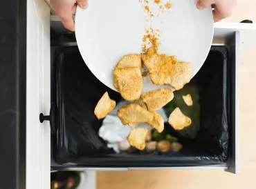 someone dumping good food into the kitchen trash