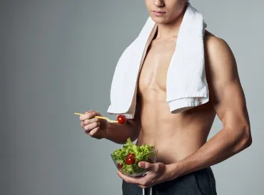 a young and muscular athlete eating a salad