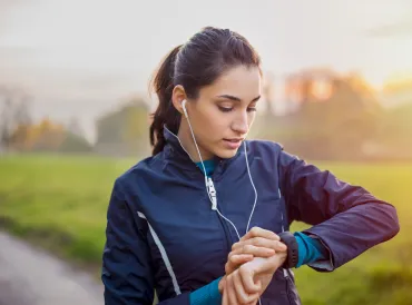 a woman walking the park, checking her smartwatch