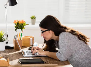 A woman on her computer hunched over working.