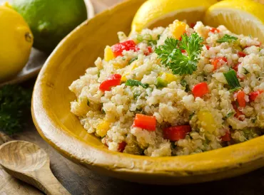 Bowl of quinoa salad with corn and chopped red pepper.