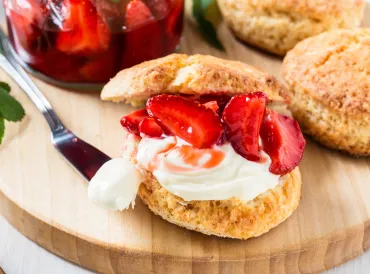 Shortcake biscuit cut open with strawberries and whipped cream in the middle.
