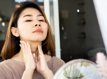 a woman rubbing her nodes on her neck below her jaw