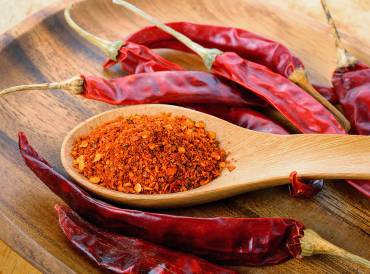 cayenne peppers and a spoon of dried cayenne powder