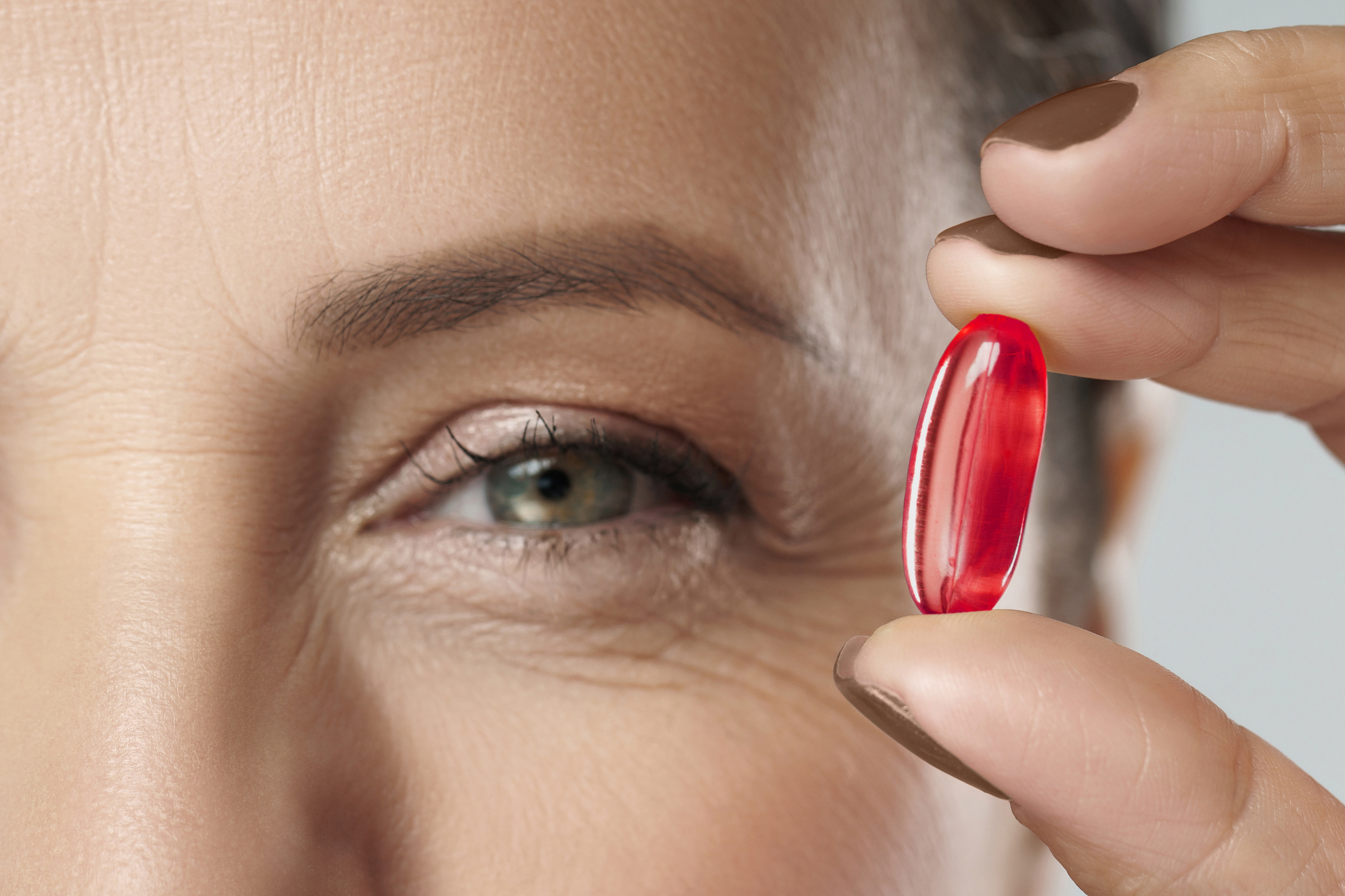 a woman holding a capsule of krill oil