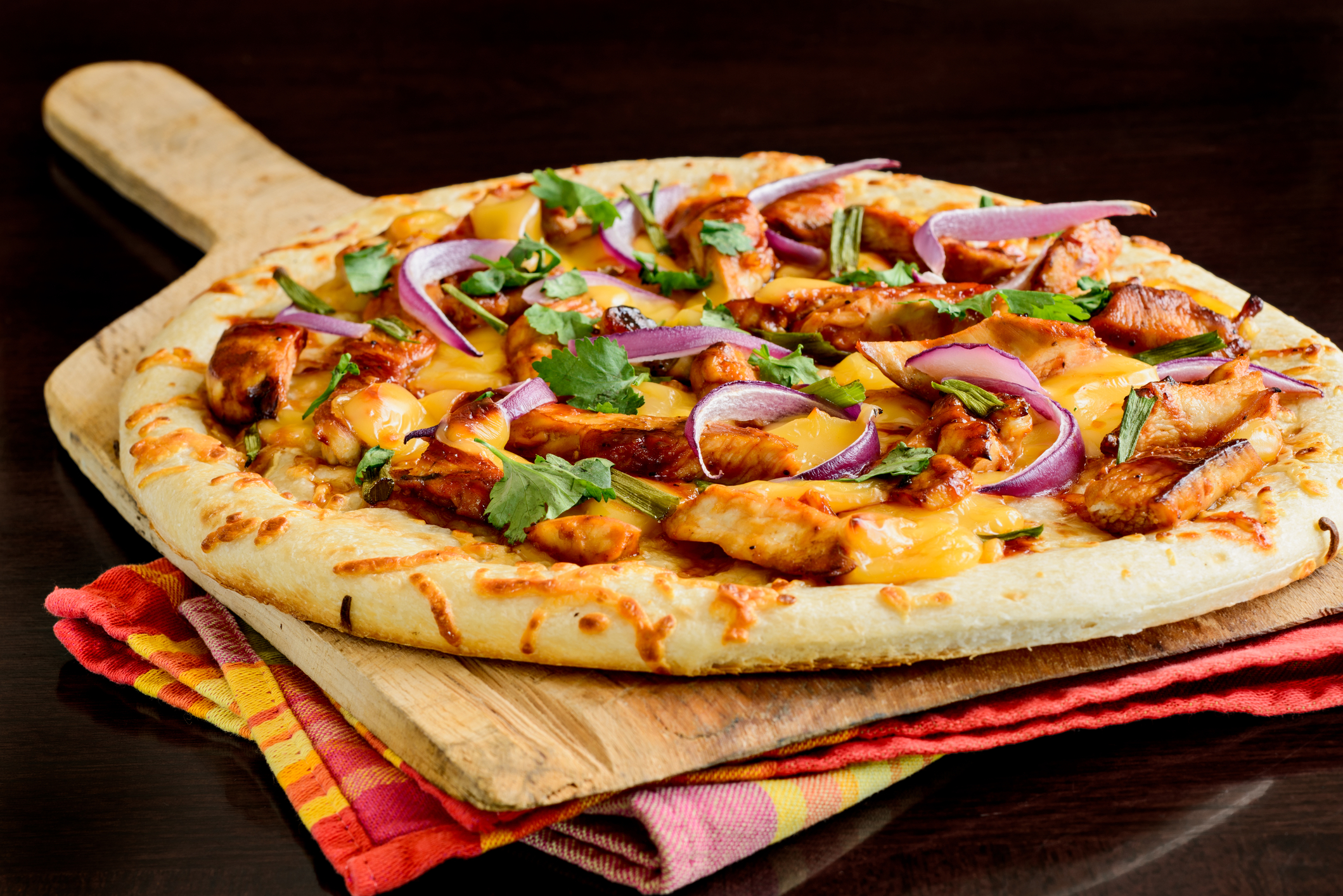 Grilled pizza with meat and purple onions on top of colorful cloths.